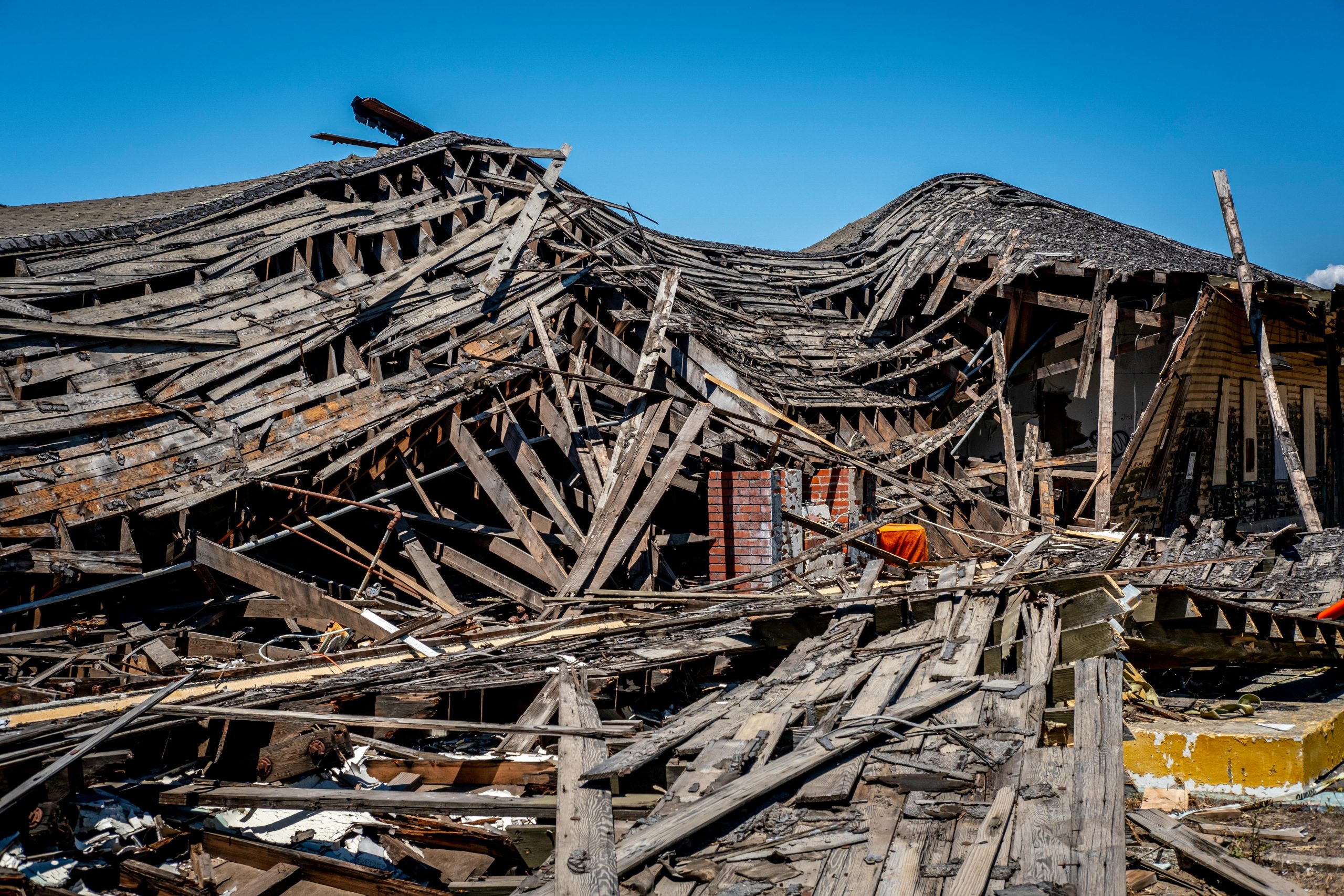 la duda por falta de crecimiento A dramatic view of a destroyed wooden building after a catastrophe, showing debris and structural failure.